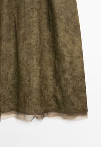 Olive green skirt with a textured floral pattern, semi-sheer overlay, and a solid hem. The fabric appears lightweight and flowy.