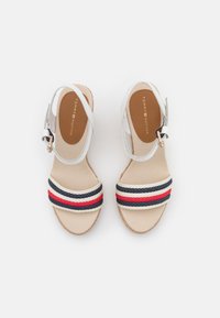 Sandali bianchi con cinturini e suola beige, dotati di bande a righe blu e rosse. Soletta marrone chiaro con branding "TOMMY HILFIGER".