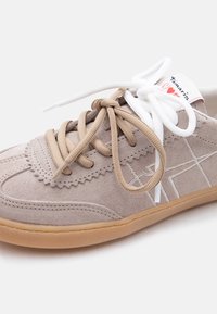 Sneaker in camoscio grigio con lacci bicolore marrone e bianco annodati a fiocco, suola marrone chiaro e dettaglio a stella cucito sul lato.
