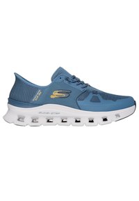 Zapatilla deportiva de color azul claro con parte superior de malla, media suela blanca y suela texturizada. Presenta un logo y acentos metálicos en el lateral.