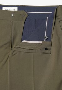 Olivgrüne Hose mit navyfarbenem Innenfutter, ausgestattet mit einem Reißverschluss, einem Knopfverschluss und dezenten Nähten entlang des Taillenbunds und der Taschen.