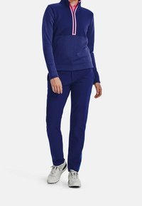 Námořnický pulovr na zip s růžovým zipem a odpovídajícím límcem; spárováno s námořnickými kalhotami s modrým bočním pruhem a světle šedými botami.