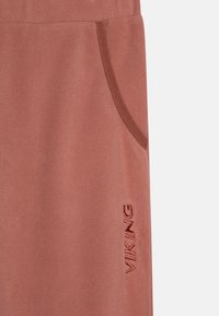 Rosa fleecebukser med sidelomme, laget av teksturert stoff, og "VIKING" brodert i mørkere tråd langs benet.