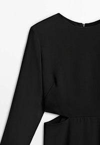 Svart klänning i mjuk tyg, med rund halsringning, långa ärmar och dragkedjeöppning bak. Urtagning vid midjan.