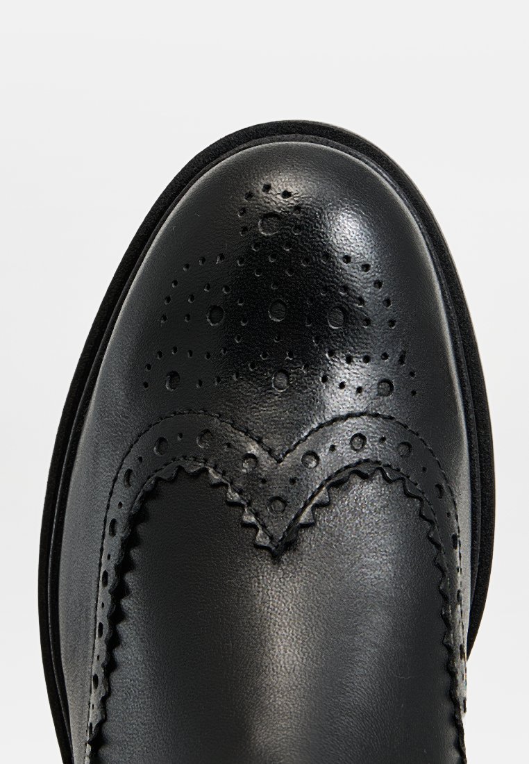 Zwarte lederen schoen met een ronde neus, voorzien van geperforeerde details en gegolfde randen langs de naad. Glad afwerking en stevige zool.