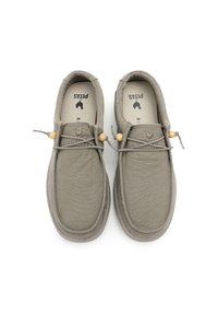 Beige canvas slip-on shoes with a textured surface, elastic laces, wooden accents, and a rounded toe design. Interior has printed branding.