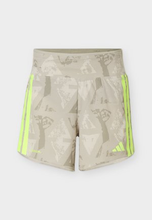 Beiget urheilushortsit, joissa on vaaleanharmaat geometriset puukuviot sekä neonkeltaiset raidat ja logot sivuilla.