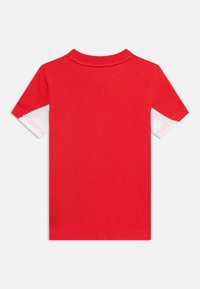 Κόκκινη κοντομάνικη μπλούζα με λευκές πανελ κάτω από τα μανίκια, με στρογγυλή λαιμόκοψη, εμφανίζεται από πίσω σε μονόχρωμο φόντο.