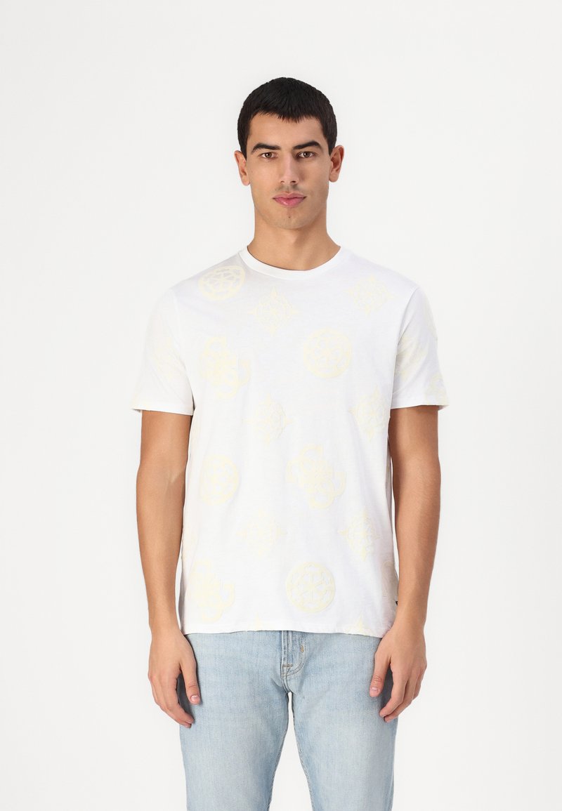 Camiseta blanca de manga corta con un sutil patrón amarillo de diseños circulares y florales. La tela parece suave y cuenta con un clásico cuello redondo.