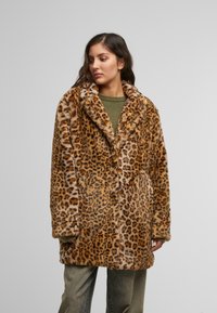 Leopardmønster faux fur-frakk med bred krage, knappestreng foran og sidelommer; varme tan- og brune nyanser med en myk tekstur.
