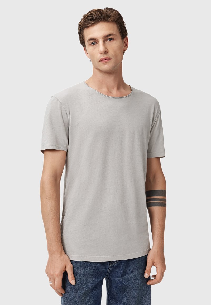 T-shirt grigio chiaro a maniche corte in morbido tessuto, con scollatura rotonda e vestibilità comoda. Presenta dettagli cuciti lungo i bordi.