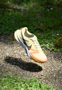 Dzeltena sporta kurpe ar acs audumu augšdaļu, melniem akcentiem un oranžu zoli. Viegls dizains ar šņorēm un polsterētu apkakli.