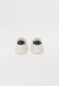 Adidași albaștri cu un finisaj texturat, având un accent din piele neagră la călcâi și o talpă din cauciuc. Design minimalist cu linii curate.