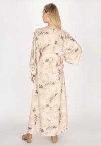 Rochie maxi dintr-un material moale și ușor, cu un fundal beige, model floral gri, mâneci largi și talie stilizată cu o curea.