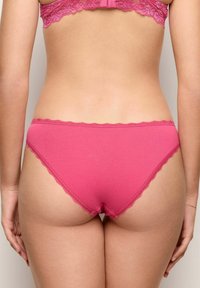 Katoenmix bikinislipje in framboosroze met golvende kanten rand. Beschikt over een zachte textuur en een gemiddelde taille.