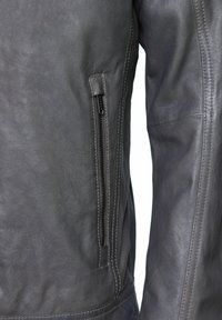 Tmavošedá kožená bunda s bočnou vreckom na zips, povrch je hladký a má jemné švy.