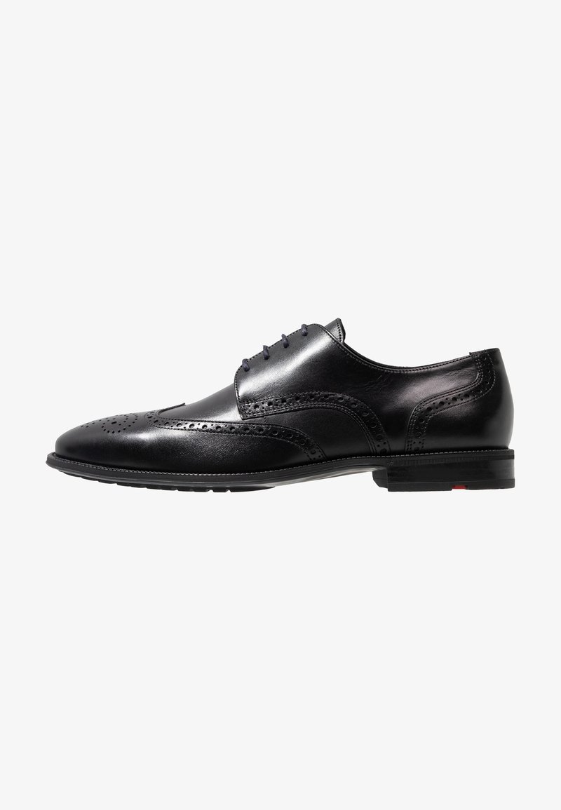 Chaussure habillée en cuir noir avec des détails de brogue, un bout arrondi, six œillets et une finition lisse avec une subtile texture sur les côtés.