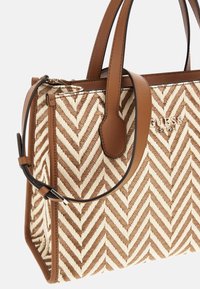Sandal og cremefarvet håndtaske med chevron-mønster lavet af vævet materiale, med brune læderdetaljer og dobbelt top-håndtag. Inkluderer justerbar rem.