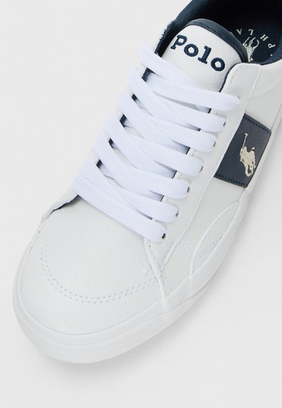 Basket en cuir blanc avec lacets blancs, bande latérale bleu marine et logo Polo brodé en blanc sur la languette et sur le côté.