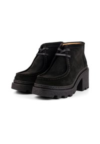 Black suede ankle boots with textured rubber soles, elevated block heels, and contrasting stitching. Features lace-up design and sturdy construction.