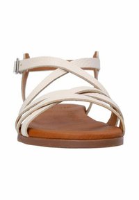 Strappy sandals made of white leather with a flat brown sole. Features crisscross straps and an adjustable ankle buckle.