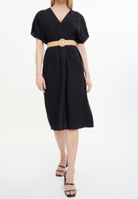 Schwarzes Leinen-Midi-Kleid mit kurzen Ärmeln, V-Ausschnitt und tailliertem Bund. Es hat einen beigen, geflochtenen Gürtel und wird mit schwarzen, hohen Sandalen kombiniert.
