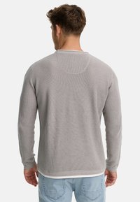 Suéter gris de punto waffle con cuello redondo, mangas largas y un ribete blanco en el dobladillo, mostrado por la parte posterior.