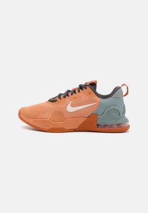Baskets basses Nike orange et bleu clair avec lacets noirs, logo Swoosh blanc et coussin d’air visible au talon.