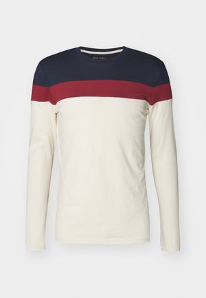 T-shirt à manches longues et col rond avec des blocs de couleurs bleu marine, rouge et crème sur la poitrine et les manches.