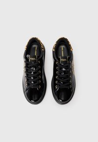 Zwarte gepatineerde leren sneakers met een binnenvoering van luipaardprint, gouden vetertjes, zwarte veters en het "KARL" logo op de tong en zijkanten.