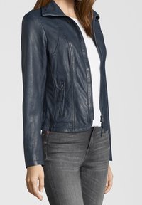 Mörkblå läderjacka med dragkedja fram, sidofickor och en skräddarsydd passform. Har en slät yta och böjda sömmar längs kroppen.