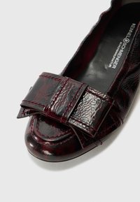 Ballerines en cuir verni bourgogne avec un large nœud texturé, un bout arrondi et des coutures contrastées sur le dessus et la semelle.