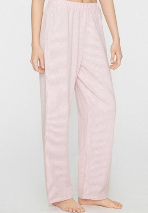 Locker sitzende, rosa-weiß gestreifte Loungehose mit elastischem Bund, barfuß getragen von einer stehenden Person.