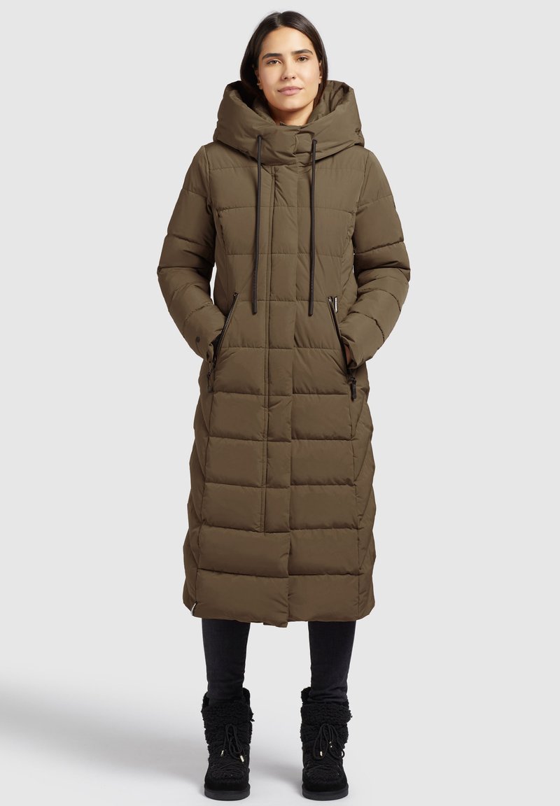 Olīvu zaļš garš pūkains mētelis ar kapuci, quilted tekstūra, divas sānu rāvējslēdzēju kabatas un auklas regulējamai piegulšanai.