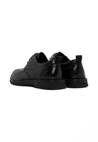 Zwarte leren schoenen met een gladde afwerking, brogue-details en een gevoerde zool. Voorzien van ronde veters en een trekloop aan de achterkant.