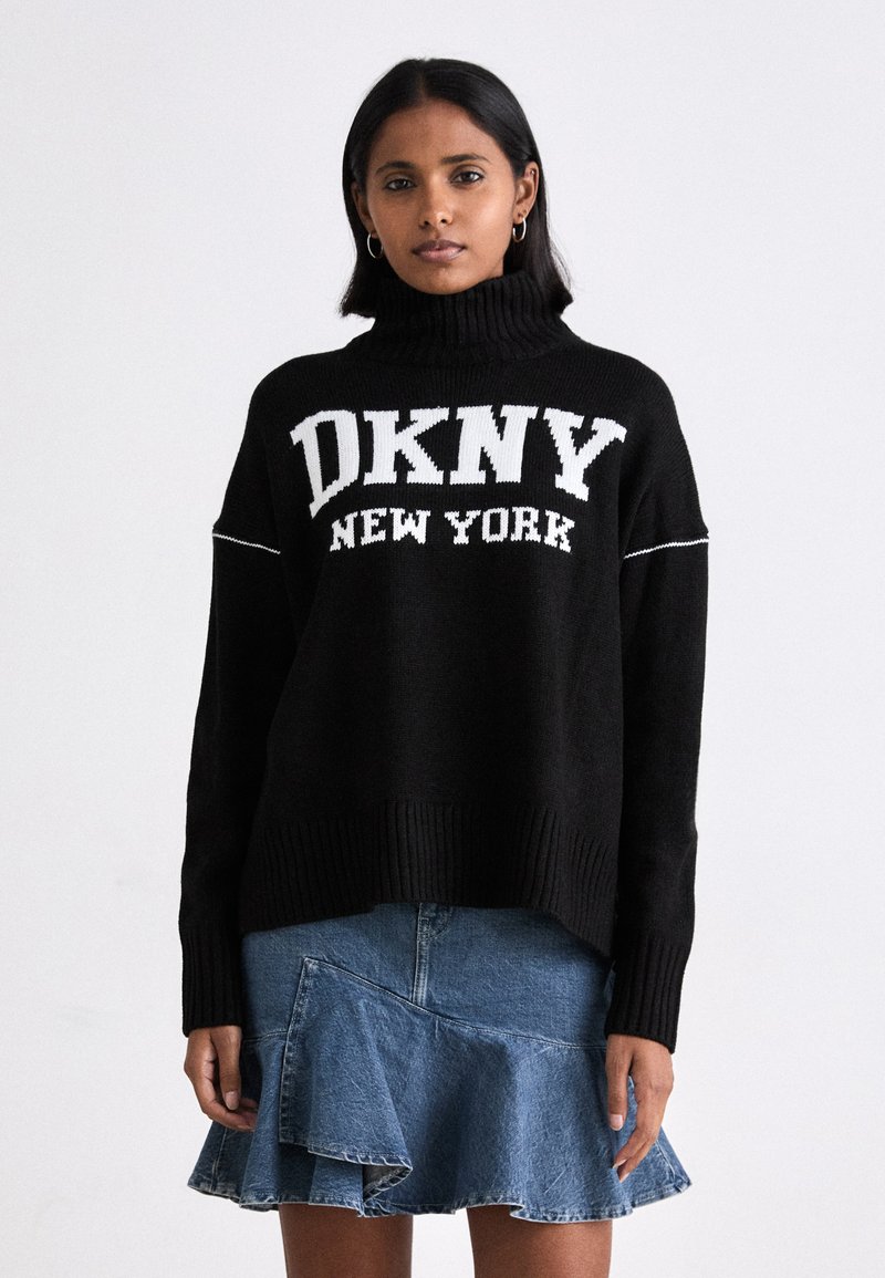 Svart stickad tröja med hög krage, med vit "DKNY NEW YORK" logotyp. Kombinerad med en jeanskjol med fläktande volangdesign.