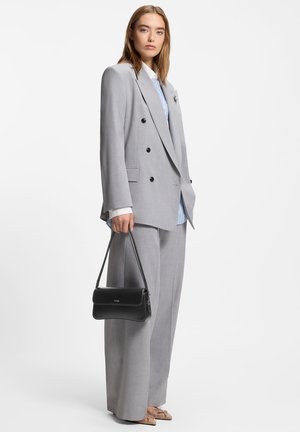 Vaaleanharmaa kaksirivinen bleiseri, yhdistetty löysiin harmaisiin housuihin. Alla sininen raitapaita ja mukana musta käsilaukku.