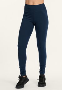 Leggings bleu marine avec une taille haute, fabriqués à partir d'un matériau doux et extensible. Présentent une texture lisse et un design ajusté, adaptés à une utilisation active.