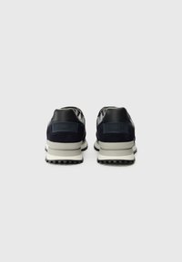 Adidași bleumarin cu un superior din piele netedă și ante, prezentând o talpă intermediară albă, o talpă exterioară din cauciuc texturat negru și un logo pe călcâi.