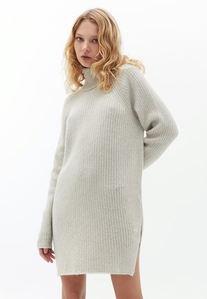 Lichtgrijze geribbelde gebreide sweaterjurk met een hoge hals, lange mouwen, zijsplitten en een zachte textuur. Eenvoudig ontwerp, zonder versieringen.