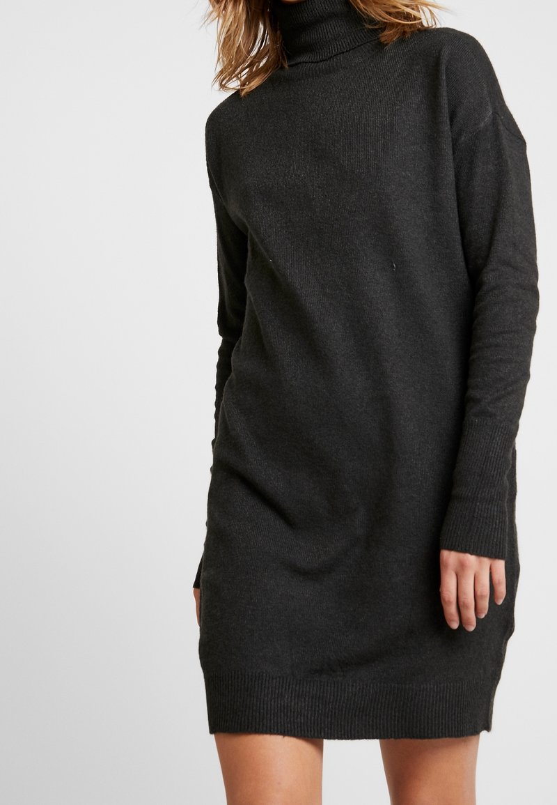 Tmavě šedé šaty s vysokým rolákem. Mají volný střih, dlouhé rukávy, žebrované manžety a lem, vyrobené z měkké pleteniny.