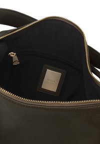 Olivazöld bőr táska belseje, sima textúrával, arany cipzárral és fekete béléssel, középen logózott lemezzel.