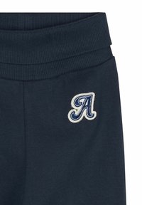 Navyblaue Jogginghosen mit einem gerippten Bund. Auf der Vorderseite befindet sich ein gestickter Buchstabe "A" in Creme und Navy. Weicher Stoff.