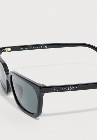 Svart rektangulära solglasögon med grå linser. Bågarna har en blank yta, gulddetaljer på gångjärnen och "JIMMY CHOO"-logotyp på skalmarna.