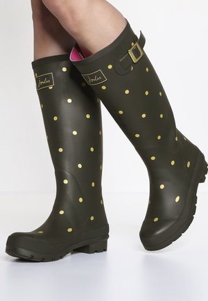 Groene rubberen regenlaarzen met grote gouden stippen, gespsluiting en een textuurzool, met een roze binnenvoering.