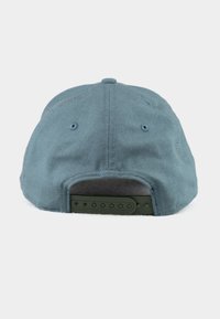 Cap features a soft, faded blue fabric with a green adjustable strap at the back. Six-panel construction with stitching accents and ventilation holes.