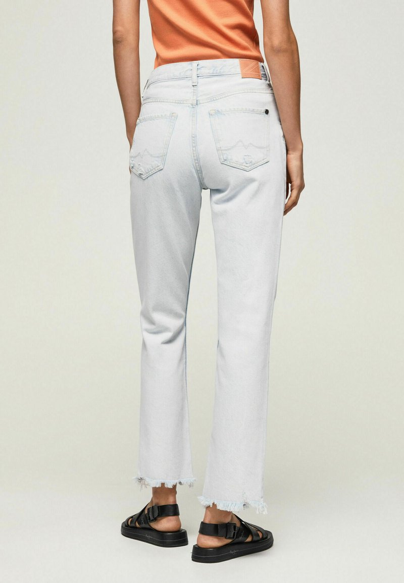 Helleblaue Denim-Jeans mit einem verkürzten, ausgefransten Saum, ausgestattet mit zwei Gesäßtaschen mit einem Berg-Logo und einem braunen Lederpatch an der Taille.