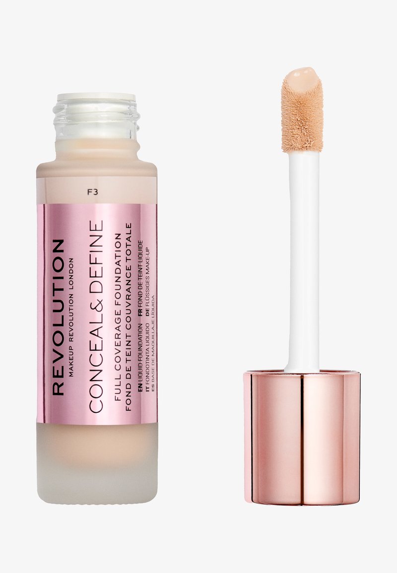 Full coverage foundation in a frosted glass bottle with a pink label, featuring a white applicator wand and a metallic rose gold cap.
