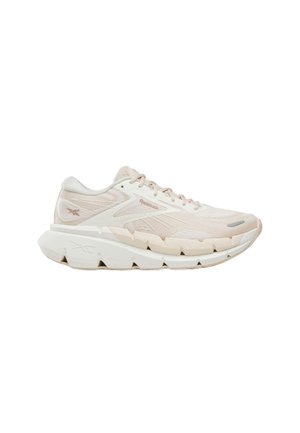 Scarpa da corsa Reebok beige e bianca con suola spessa e testurizzata e chiusura con lacci, vista laterale su sfondo bianco.