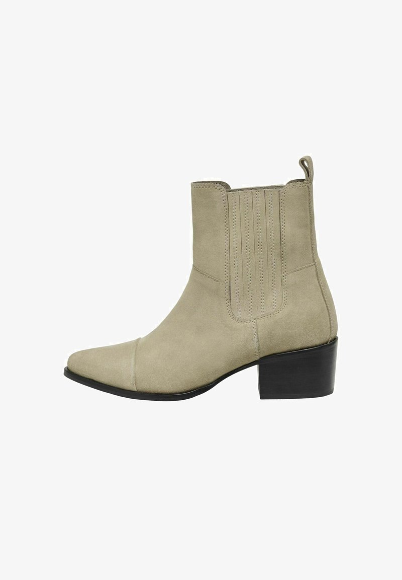 Botín de ante beige con punta afilada y tacón cuadrado de 4 cm. Presenta costuras verticales en los laterales y una tira en la parte trasera.